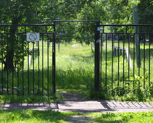 A passage through a lattice fence to a grassy sports field