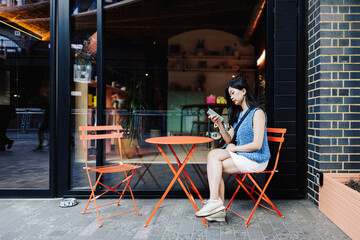 Young woman using smartphone at outdoor cafe in urban setting