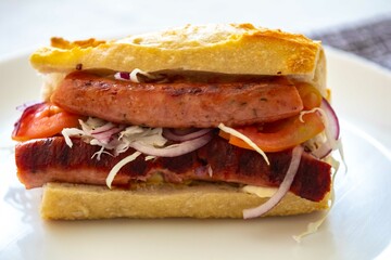 Traditional Argentine sandwich known as choripan prepared with roasted chorizo, chimichurri, cabbage, tomato, onion and sourdough bread. Real food