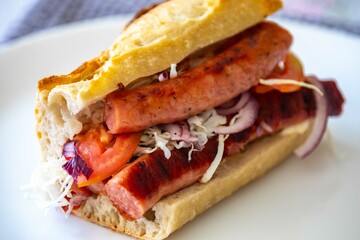 Traditional Argentine sandwich known as choripan prepared with roasted chorizo, chimichurri, cabbage, tomato, onion and sourdough bread. Real food