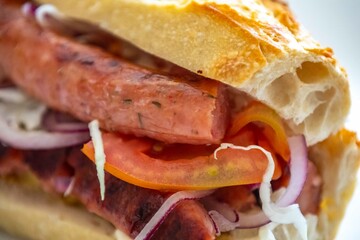 Traditional Argentine sandwich known as choripan prepared with roasted chorizo, chimichurri, cabbage, tomato, onion and sourdough bread. Real food