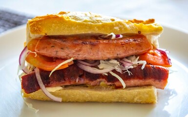 Traditional Argentine sandwich known as choripan prepared with roasted chorizo, chimichurri, cabbage, tomato, onion and sourdough bread. Real food