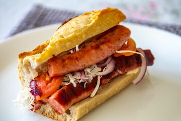 Traditional Argentine sandwich known as choripan prepared with roasted chorizo, chimichurri, cabbage, tomato, onion and sourdough bread. Real food