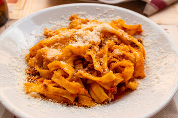 Tagliatelle pasta with bolognese sauce and grated cheese on a table