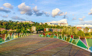 Multicolored mosaic pedestrian bridg on the background of blue sky with clouds and the town, Coimbra, Portugal