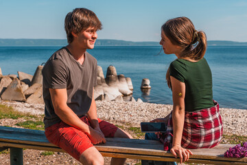 A date between a teenage boy and a girl on the riverbank in summer