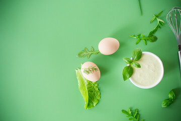 homemade mayonnaise with herbs in a bowl on a green background