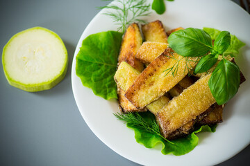 Fried zucchini slices with salad greens on a gray background