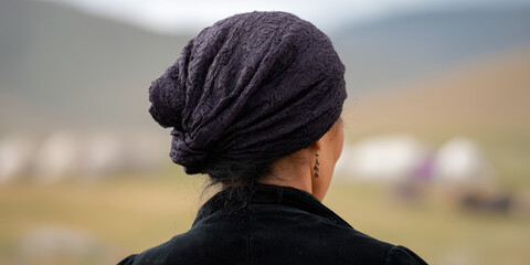 Woman wearing headscarf gazes at blurred landscape