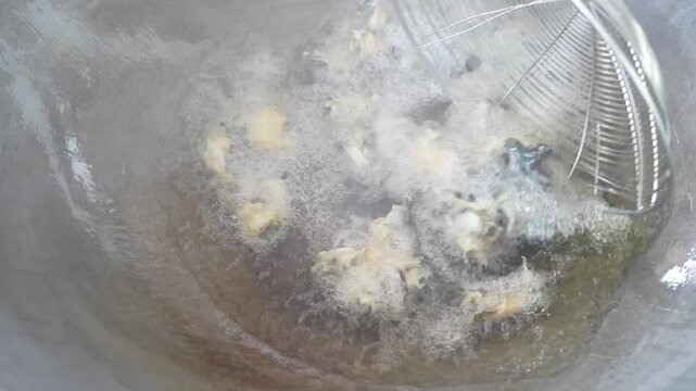 Traditional cooking method of frying frog skin in a pan with oil