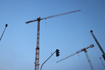 Tower cranes at sunset on a construction site, symbolizing growth and development.