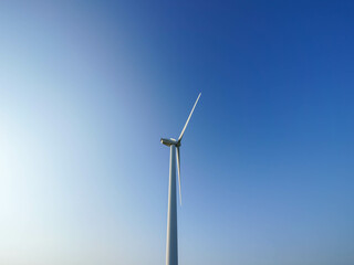 A single wind turbine rises gracefully into the clear blue sky