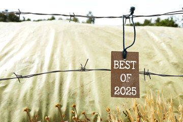 Brown Card Tag Labeled 'Best of 2025' on Barbed Wire Fence