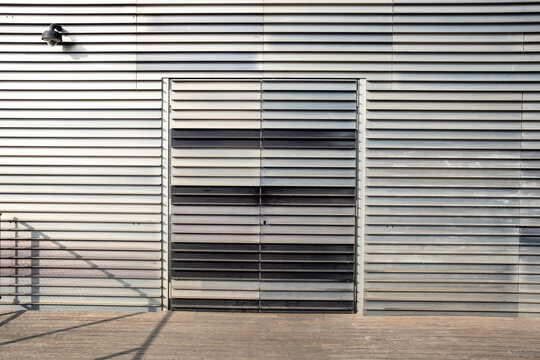Metallic facade with horizontal lines and minimal shadow, urban background with geometric pattern and industrial design, ideal for commercial copyspace