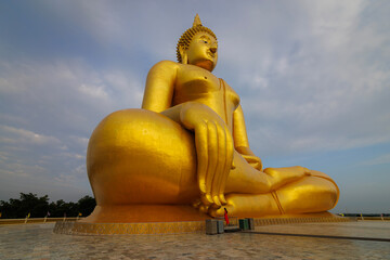 The largest golden Buddha statue with green rice field foreground at Wat Muang Temple in Ang Thong Province, Thailand.