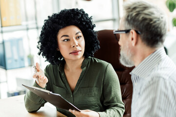 Professional business discussion between coworkers in an office setting showcasing teamwork, collaboration, and diverse backgrounds.
