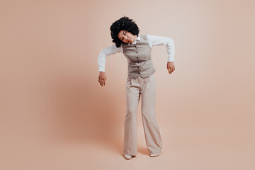 Confident businesswoman in stylish formal wear posing against a beige background showing a unique...