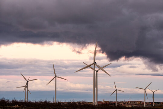 Row of windmills at dusk with vibrant clouds in Aragon, Spain, green technology landscape and renewable power transition under natural light