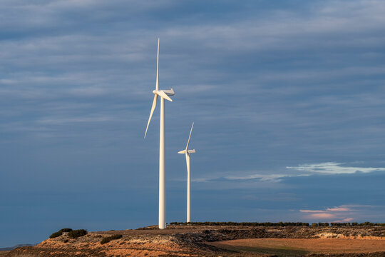 Wind turbines on desertic terrain with soft sky tones in Aragon, Spain, clean energy system and ecological electricity production from wind sources