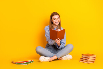 Young woman reading a book against a vibrant yellow background seeking educational inspiration