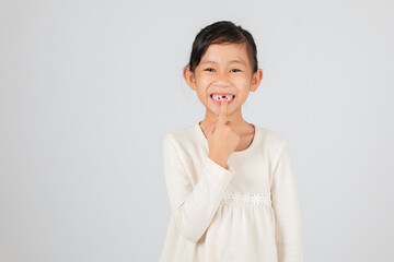 Happy child pointing to a tooth gap with joy. The dentist discusses tooth loss and the importance of monitoring the growing tooth gap for healthy teeth. isolated white background