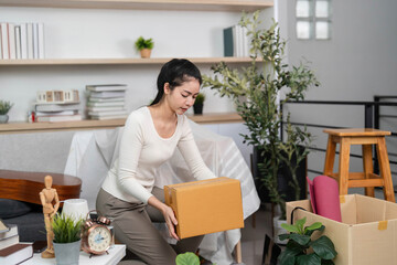 Moving and Organizing. Woman lifting a box while packing belongings at home.