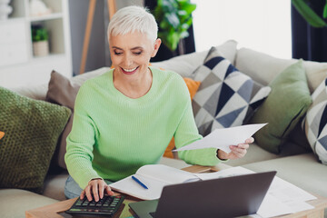 Woman managing financial tasks at home with technology and focused expression while enjoying a...
