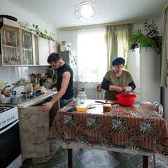 Cooking together in a cozy kitchen as a young man helps an elderly woman prepare a delicious meal...