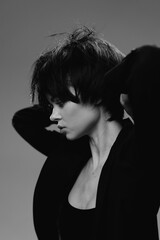 Black and white portrait of a young woman with short hair and thoughtful expression wearing dark...