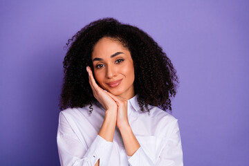 Young stylish woman in a white shirt posing on a vibrant purple background with a charming smile...
