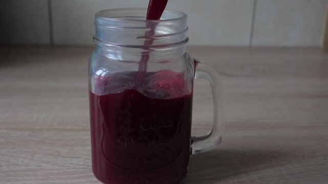 Pouring freshly made beetroot juice into glass. Slow motion shot