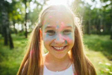 Smiling Caucasian girl with powder on face in sunny forest. Close-up portrait of childhood joy,...