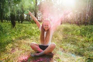 Caucasian girl throws powder in forest while smiling. Childhood joy, emotional release, authenticity, creative freedom and playful expression in natural summer light.
