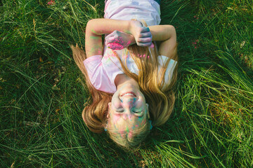 Top-down portrait of joyful girl smiling with closed eyes, covered in colorful powder. Concept of...