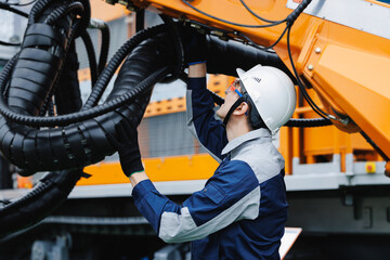 Naklejka na ściany i meble Engineer doing check on installation hydraulic hoses of industrial geological drilling machine for oil
