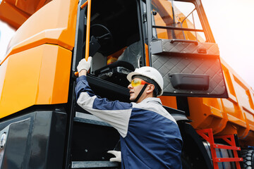 Male worker operating heavy truck machinery in mining site with safety gear and equipment