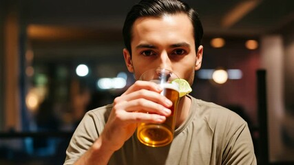 Young man sipping refreshing limeinfused drink at a cozy bar setting