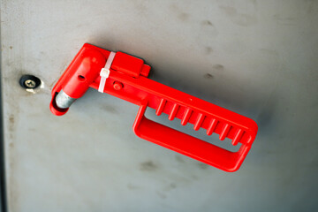 A red plastic handle that has a screw affixed to it firmly