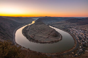 Sunrise over the Moselle. The river winds through a valley in a narrow loop surrounded by vineyards...