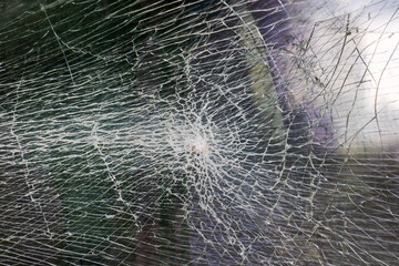 A close up image of a broken glass window showing a hole in it