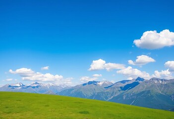 Fototapeta premium Serene green lawn overlooking a majestic mountain range under a clear blue sky with fluffy white clouds, mountain landscape, view