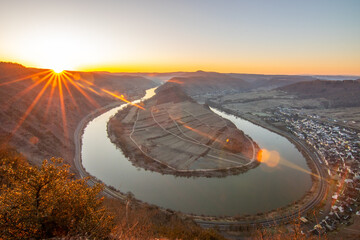 Sunrise over the Moselle. The river winds through a valley in a narrow loop surrounded by vineyards...