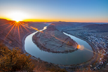 Sunrise over the Moselle. The river winds through a valley in a narrow loop surrounded by vineyards...