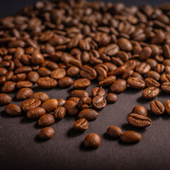 Dark roasted coffee beans arranged in a scattered manner on a textured surface, highlighting their rich color and shape in warm lighting