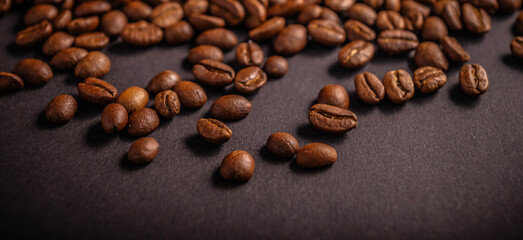 Close-up view of coffee beans scattered artfully on a dark surface, highlighting their natural hues...