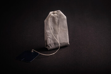 Close-up of a tea bag on a dark surface, highlighting its shape and texture in a serene setting...