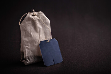 A tea bag with a simple tag sits on a dark tabletop, creating a warm and inviting atmosphere during...