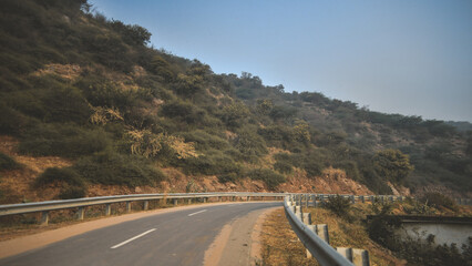 A beautiful, peaceful early morning view from the Aravalli hills in Haryana, India. A road with...