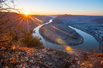 Sunrise over the Moselle. The river winds through a valley in a narrow loop surrounded by vineyards...