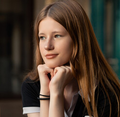 Close-up portrait of a thoughtful young woman resting her chin on her hands, looking into the distance. A serene image reflecting dreams, hopes, and inner desires